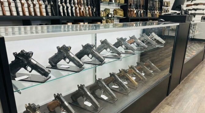 Handguns displayed in a gun store showcase, relevant to 2026 handgun market trends.