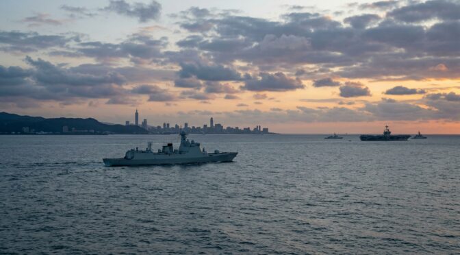 Taiwan Strait: Warship patrols near Taiwan skyline, with U.S. Navy carrier group in background. Deterrence analysis.