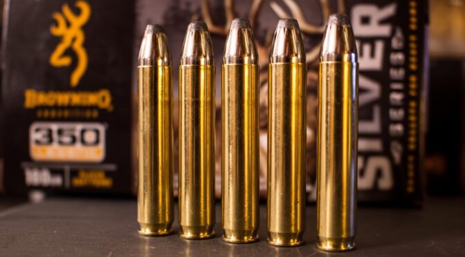 Five Browning 350 Legend cartridges stand in a row, with a box of ammunition in the background.