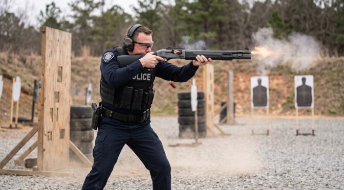 Police officer shooting a shotgun at a target in a training range