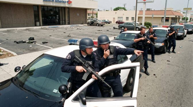 SWAT officers in tactical gear with rifles outside a bank.