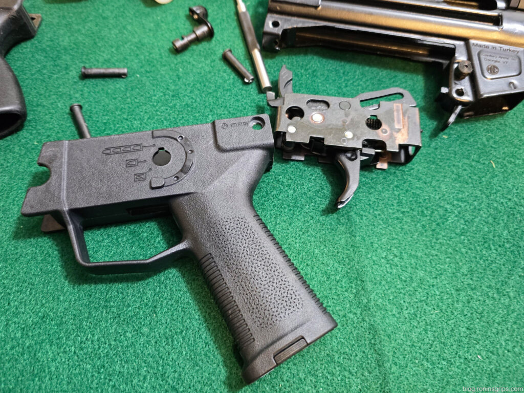 Disassembled firearm trigger group and receiver housing on a green surface