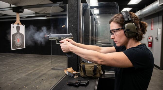 Woman fires handgun at target range, ejecting casing.